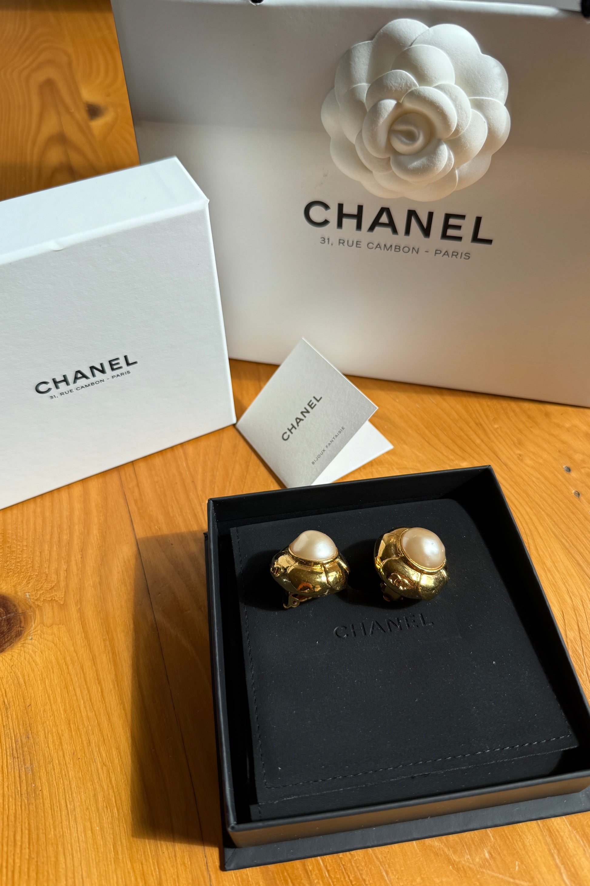 Paire de clips d’oreilles Chanel vintage en perle baroque et métal doré, dans écrin noir avec boîte et sac Chanel.