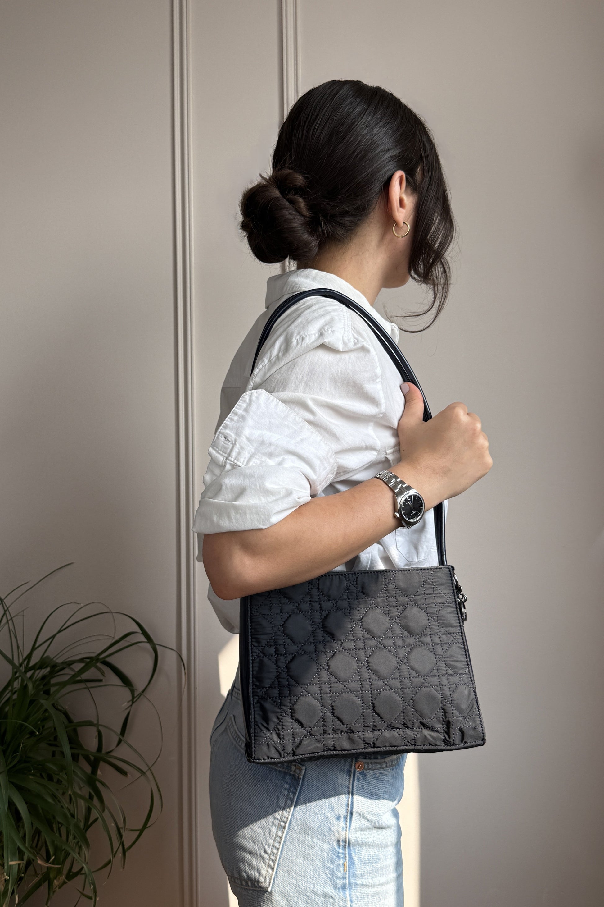 Femme portant un sac Christian Dior bleu marine à l'épaule, en chemise blanc et jean