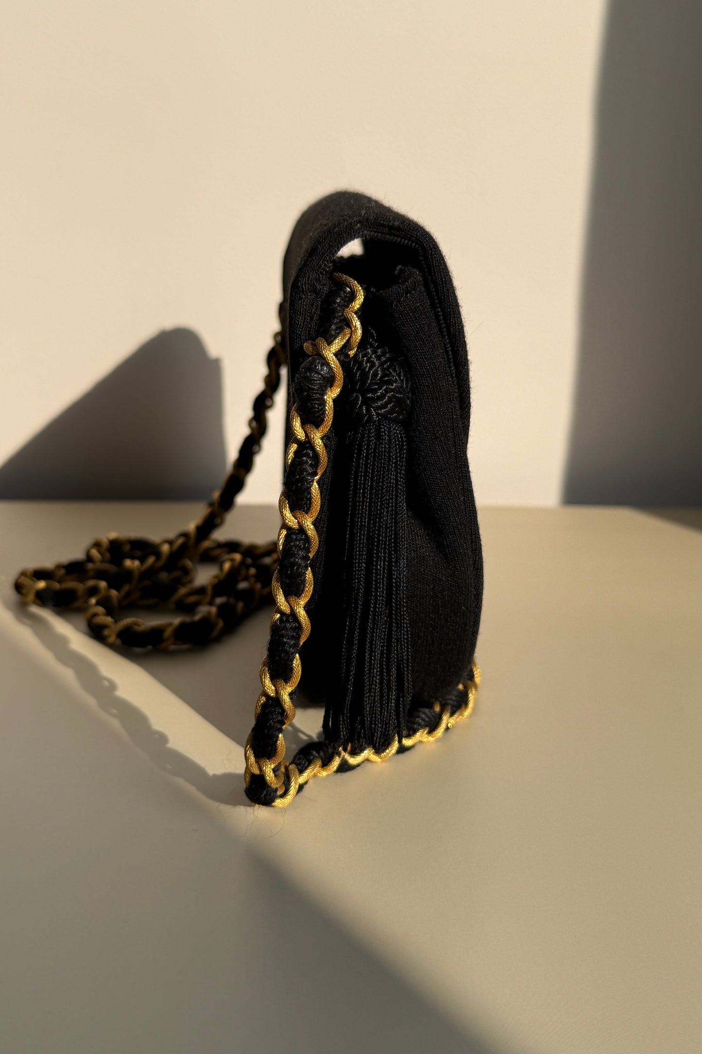 Sac Chanel en tissu matelassé noir avec chaîne dorée, côté