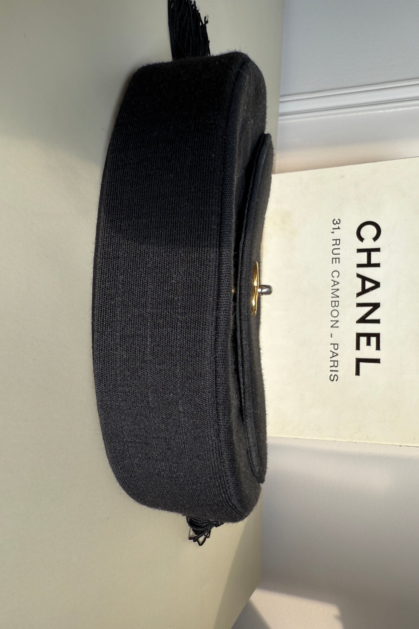bas du sac Chanel vintage en tissu matelassé noir, présentée avec sa boîte d’origine rue Cambon Paris.