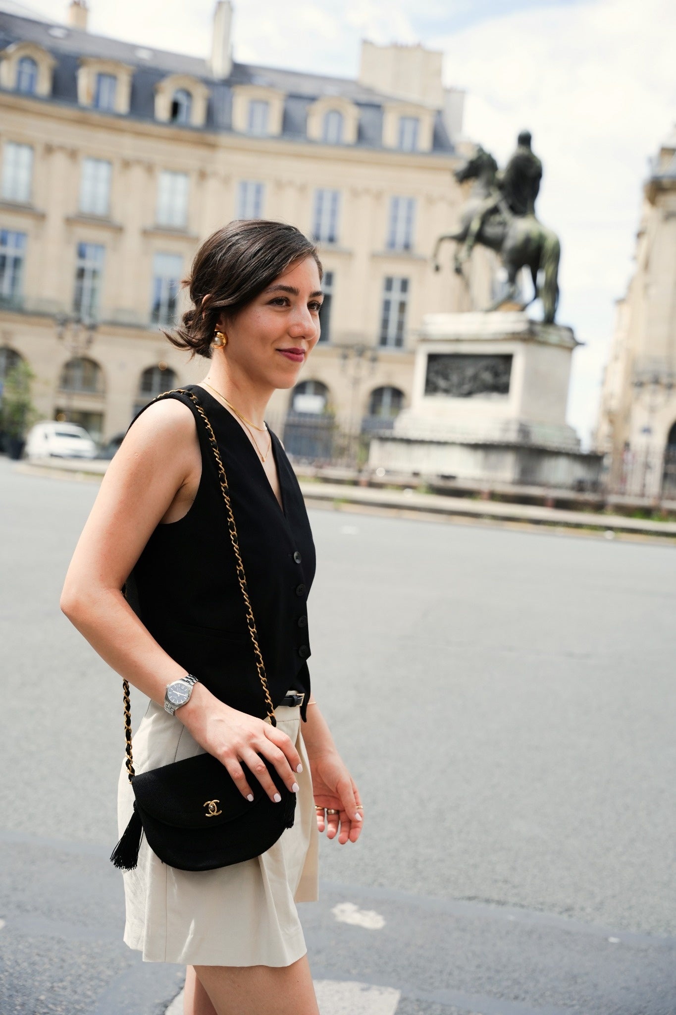 Sac Chanel noire en tissu matelassé avec chaîne dorée, porté en bandoulière dans les rues de Paris.