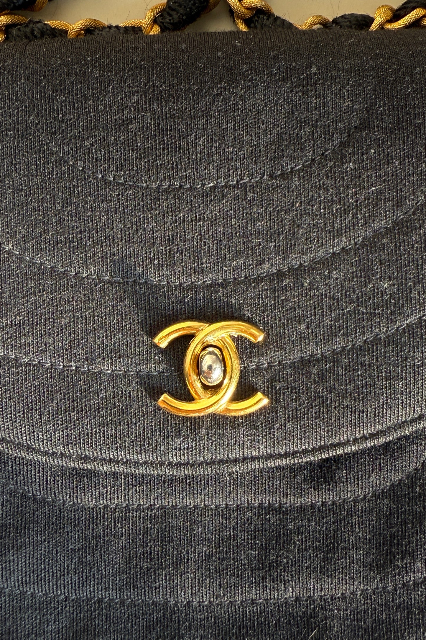 Détail fermoir du sac Chanel noir, logo CC doré et chaîne en cuir et métal doré.