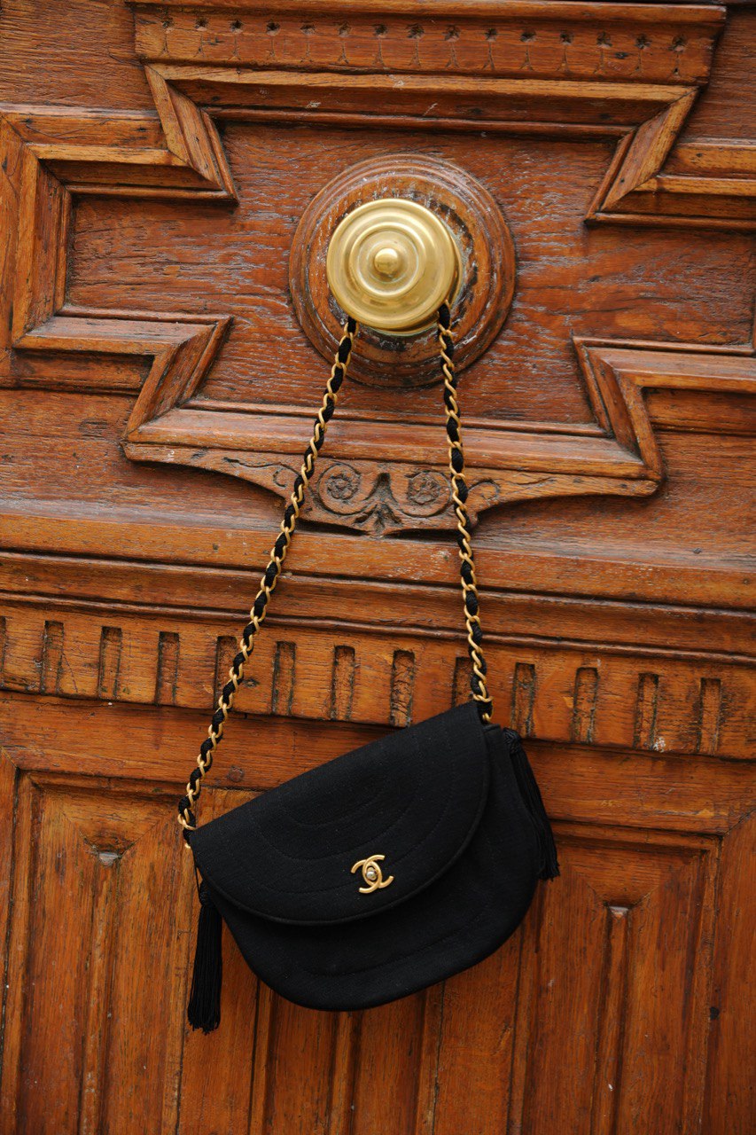 sac Chanel vintage en toile noir avec chaîne dorée sur une porte 